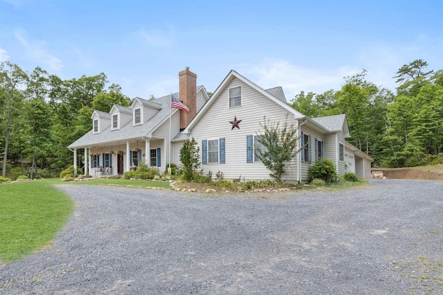 cape cod home with a chimney, a shingled roof, covered porch, a front yard, and driveway