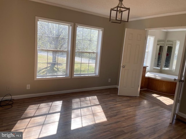unfurnished dining area featuring baseboards, an inviting chandelier, dark wood-style flooring, ornamental molding, and a textured ceiling