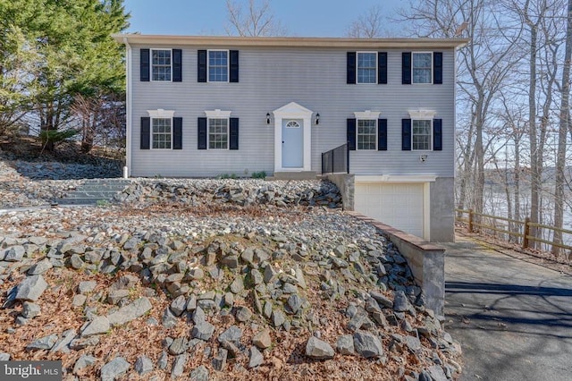 colonial-style house with an attached garage, driveway, and fence