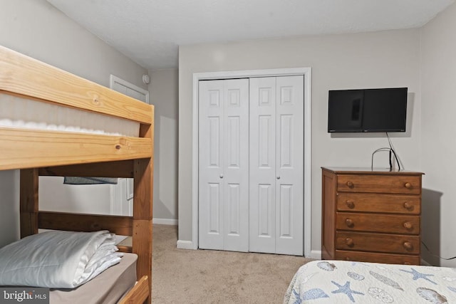 carpeted bedroom with baseboards and a closet