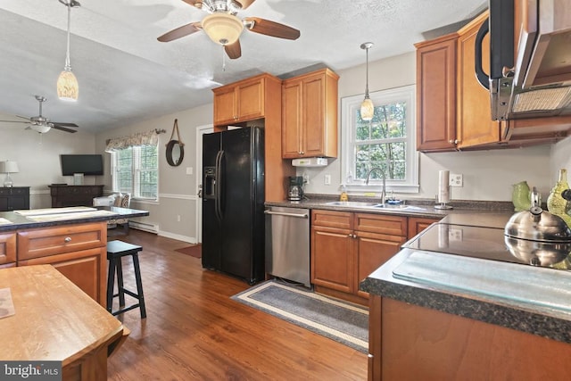 kitchen featuring dark wood-style flooring, a sink, appliances with stainless steel finishes, pendant lighting, and dark countertops