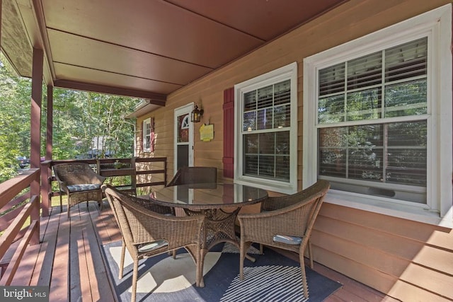 wooden terrace featuring outdoor dining area and covered porch