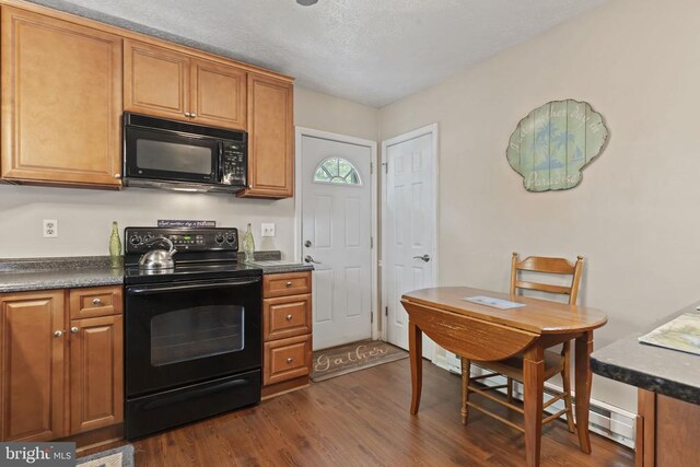 kitchen with dark countertops, black appliances, dark wood-style floors, and brown cabinetry