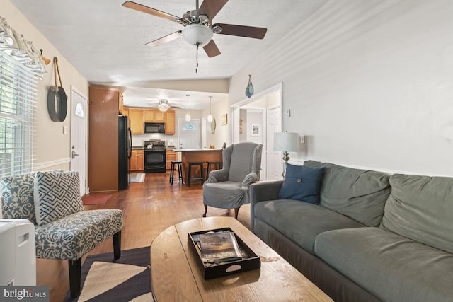 living area featuring ceiling fan, lofted ceiling, and dark wood-style floors