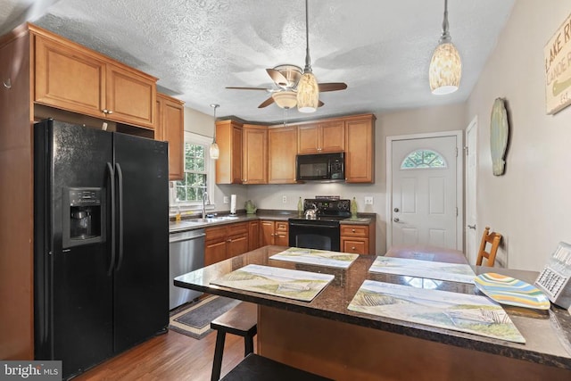 kitchen with black appliances, decorative light fixtures, dark countertops, and brown cabinets