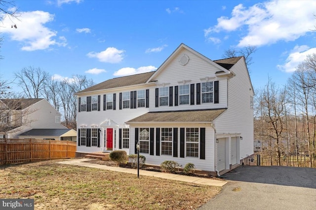 view of front of house with aphalt driveway, an attached garage, and fence