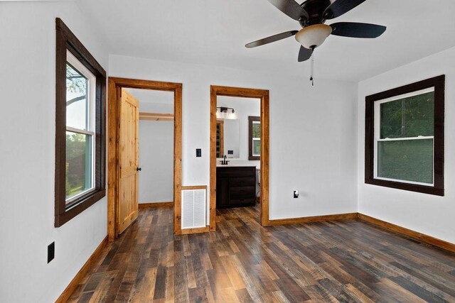 unfurnished bedroom with ensuite bathroom and dark hardwood / wood-style flooring