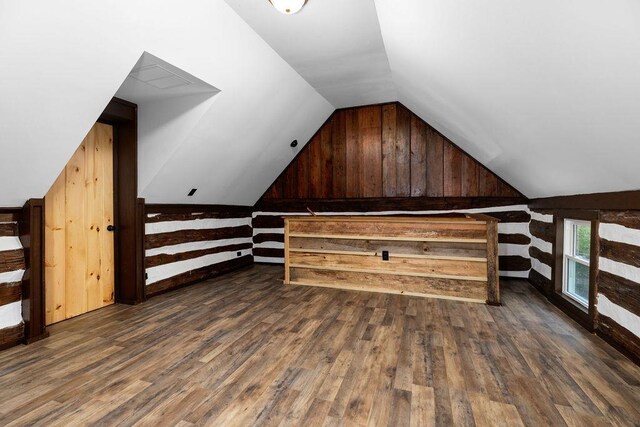 additional living space with dark hardwood / wood-style flooring, wooden walls, and lofted ceiling