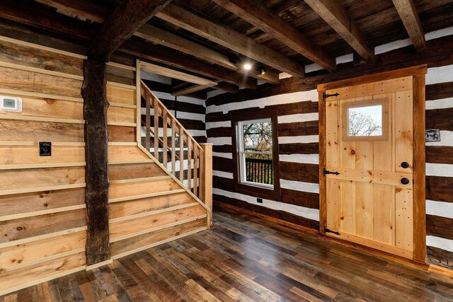 entrance foyer featuring dark wood-type flooring, wood ceiling, wooden walls, and beamed ceiling