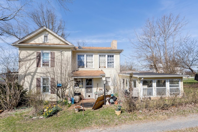 back of property featuring a chimney and a sunroom