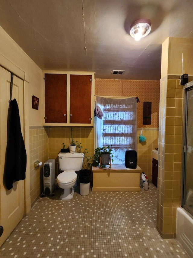 full bath with toilet, visible vents, tile walls, a tub, and an enclosed shower