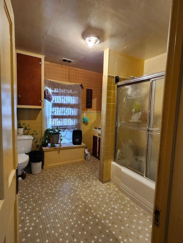 full bathroom featuring visible vents, tile walls, toilet, and combined bath / shower with glass door