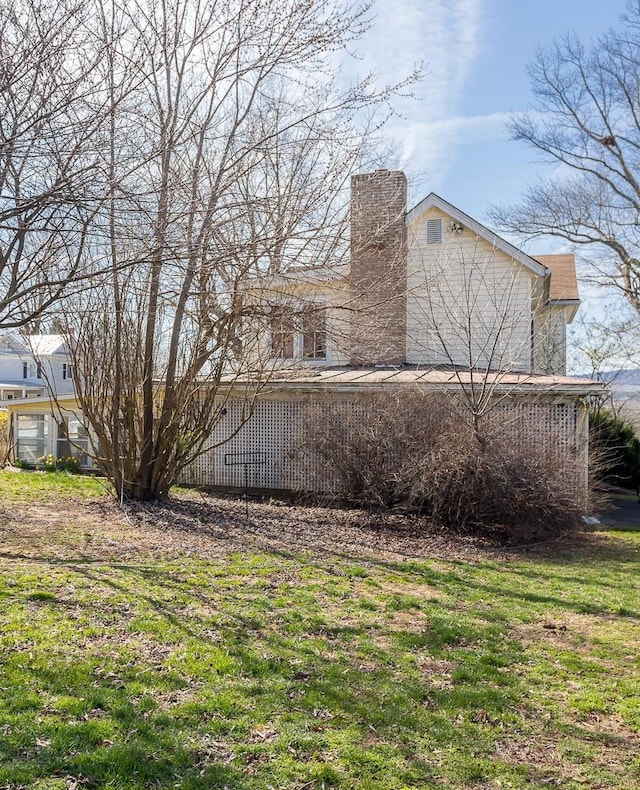 view of side of property featuring a chimney and a yard