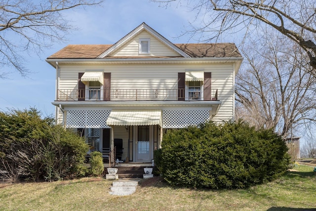 view of front of home with a balcony and a front lawn