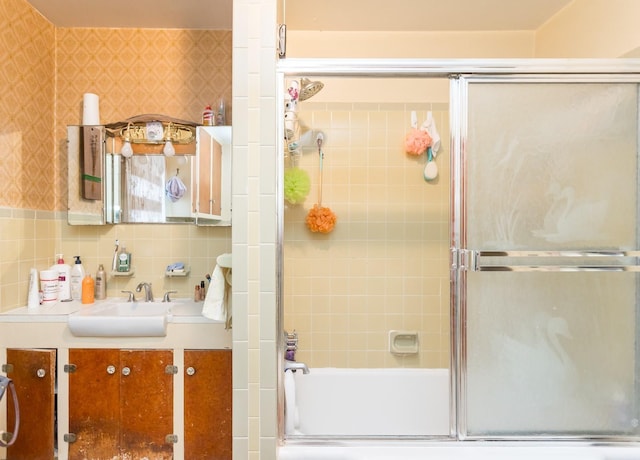 full bath with combined bath / shower with glass door, decorative backsplash, vanity, and wallpapered walls