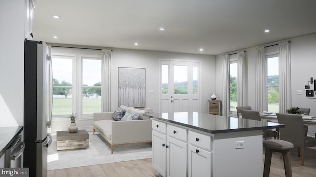 kitchen with dark countertops, freestanding refrigerator, open floor plan, white cabinets, and a kitchen island