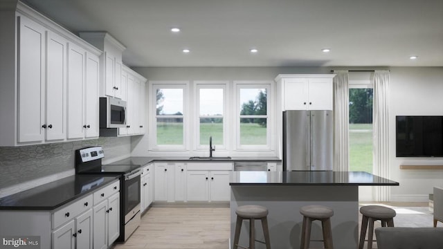 kitchen with dark countertops, white cabinets, stainless steel appliances, and a sink