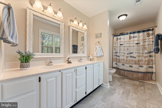 bathroom featuring double vanity, visible vents, toilet, and a sink
