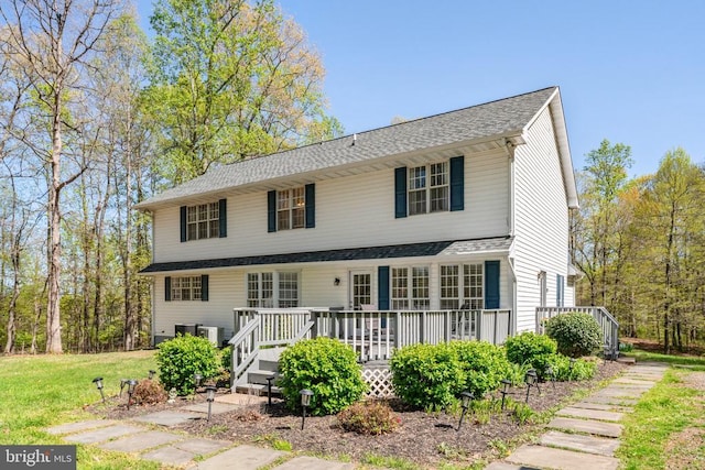 view of front of home with a wooden deck, a shingled roof, and a front yard