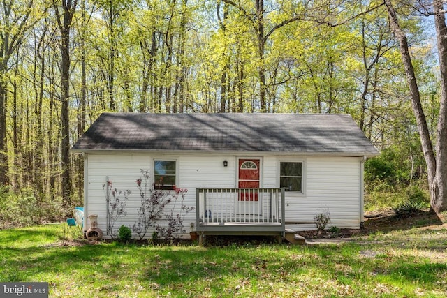view of front facade featuring roof with shingles and a front yard
