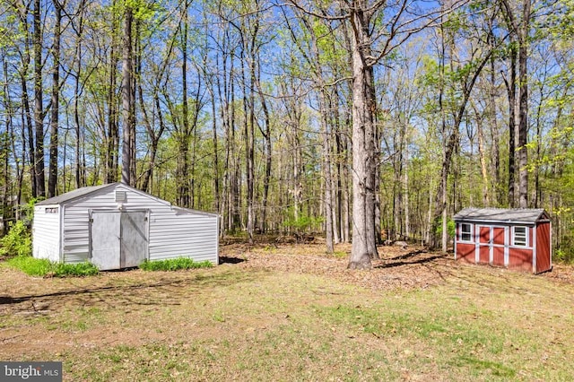 view of yard with a forest view, an outdoor structure, and a storage shed