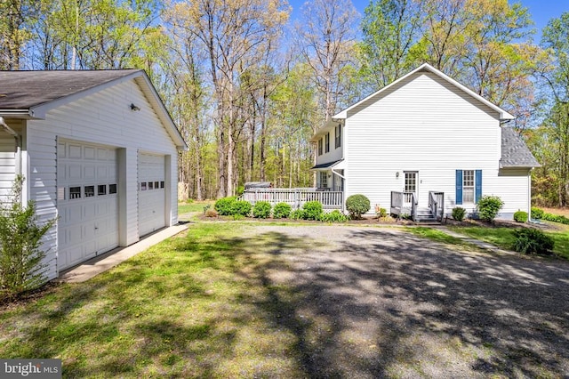 view of side of home featuring roof with shingles, a yard, a detached garage, and a deck