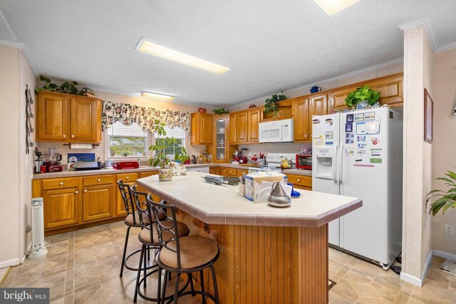 kitchen featuring a kitchen breakfast bar, ornamental molding, a kitchen island, and white appliances