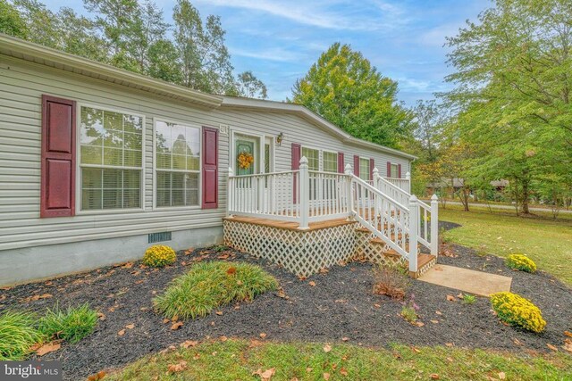 view of front facade with a wooden deck and a front yard