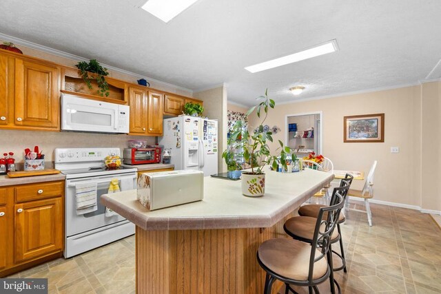 kitchen with crown molding, white appliances, a breakfast bar, and a kitchen island