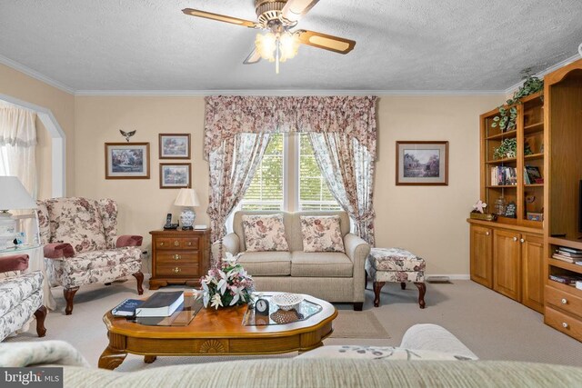 carpeted living room featuring ceiling fan, ornamental molding, and a textured ceiling