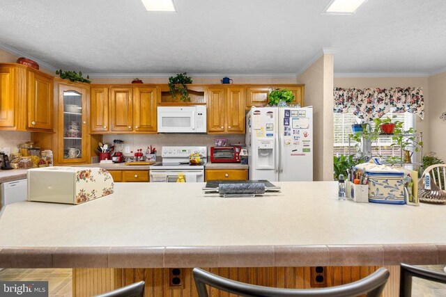 kitchen with crown molding, white appliances, and a breakfast bar area