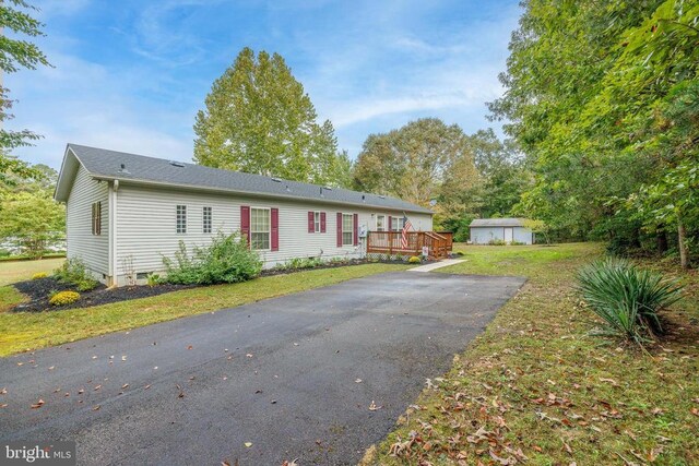 exterior space featuring a storage shed, a deck, and a front yard