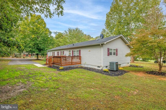 back of property with central AC, a deck, and a lawn