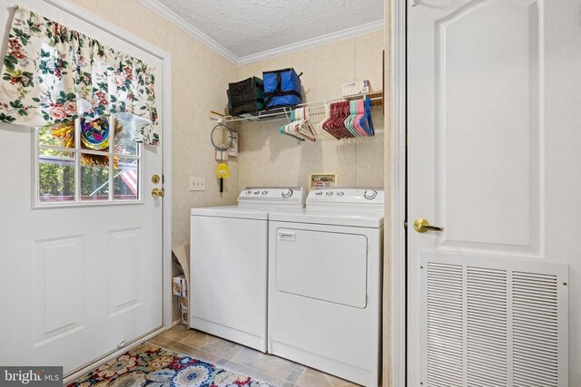 clothes washing area featuring crown molding, washing machine and clothes dryer, and a textured ceiling