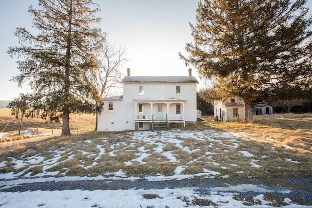 snow covered rear of property with a storage shed and a porch