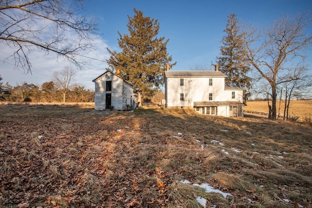 back of house with an outdoor structure and a rural view