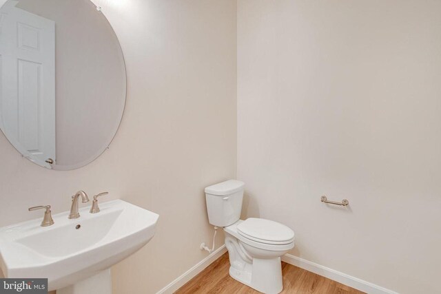 bathroom featuring wood-type flooring, toilet, and sink