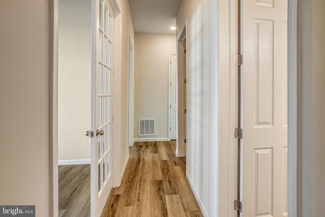 hallway with light hardwood / wood-style flooring and french doors