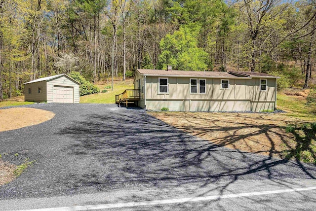 view of front of home featuring an outdoor structure, a garage, driveway, and a forest view