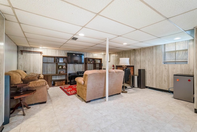 living room featuring a paneled ceiling and wood walls