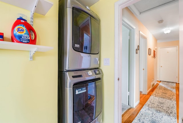 laundry room with stacked washer / drying machine and light hardwood / wood-style floors