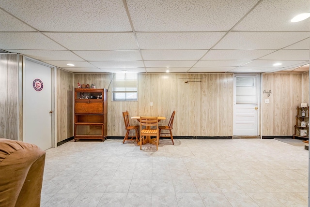 dining space with a drop ceiling and wood walls