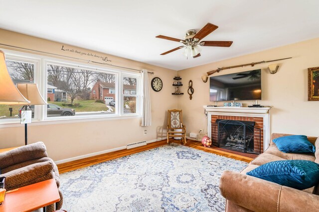 living room with ceiling fan, hardwood / wood-style floors, and a brick fireplace