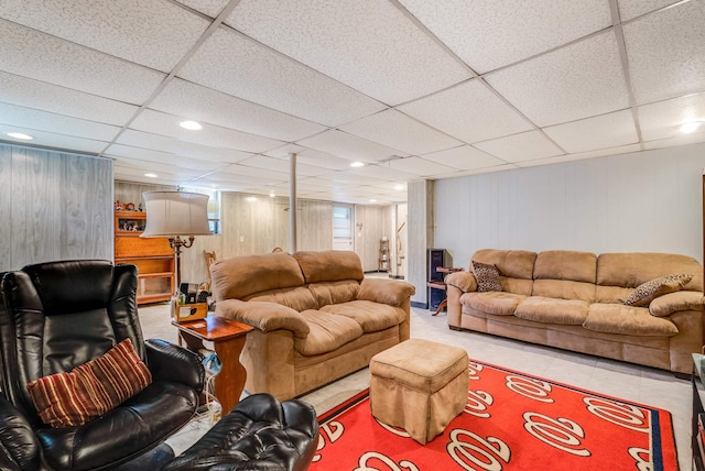 living room featuring a paneled ceiling, wooden walls, and tile patterned flooring