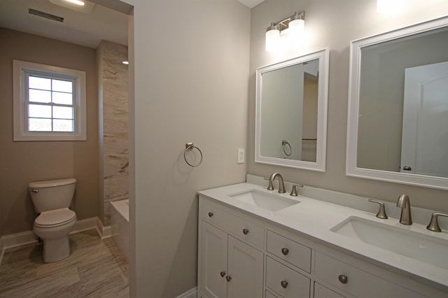 full bathroom featuring tiled shower / bath combo, vanity, and toilet