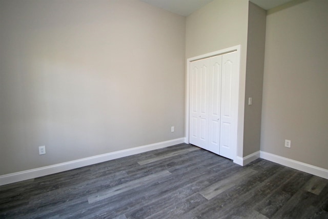 unfurnished bedroom with dark wood-type flooring and a closet