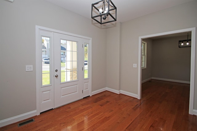 doorway to outside featuring dark wood-type flooring and an inviting chandelier