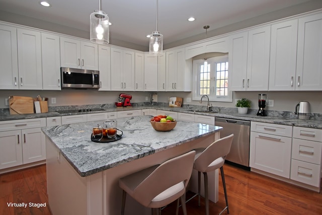 kitchen with white cabinetry, appliances with stainless steel finishes, a center island, and sink