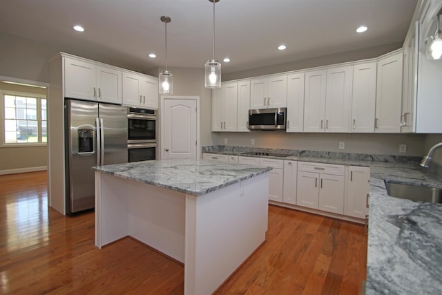 kitchen featuring white cabinetry, stainless steel appliances, a center island, and sink