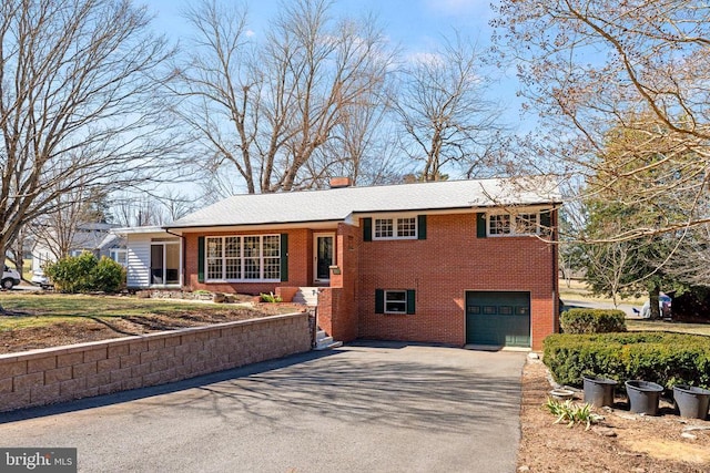 tri-level home featuring a garage, brick siding, and driveway